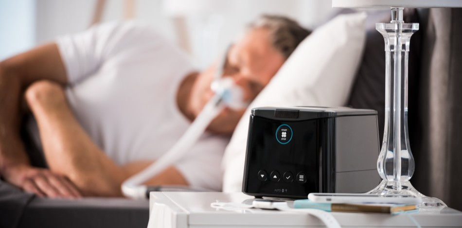 Man sleeping on a bed wearing a sleep respirator